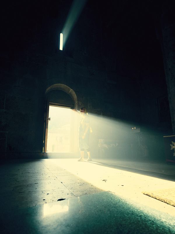 A shaft of daylight falling through a doorway into a dark stone hall