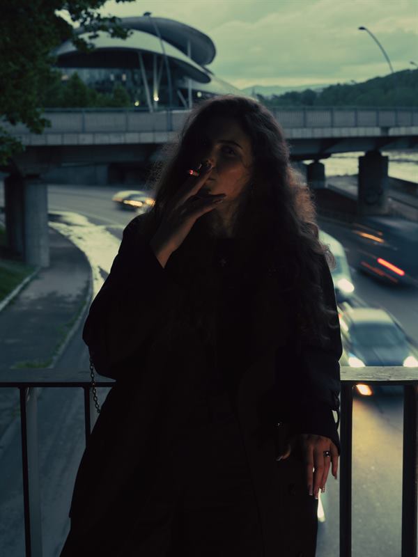 A woman on a footbridge over a motorway at dusk