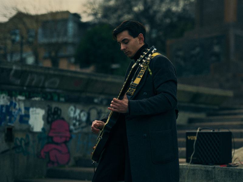 A guitarist tuning up in front of a graffiti wall
