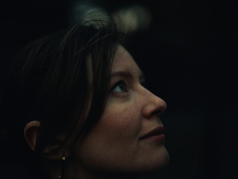 A woman looking upward, lit from above against black
