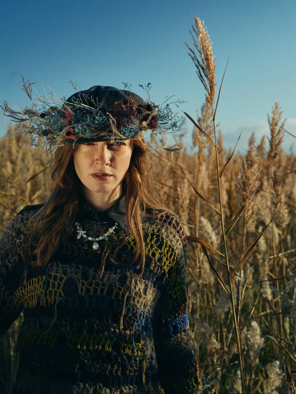 A woman in a flower crown standing in tall dry reeds