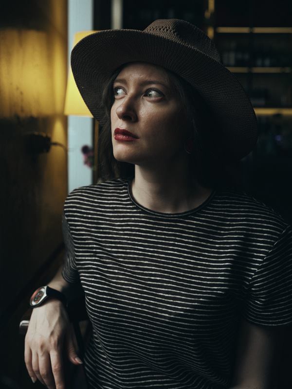 A woman in a wide-brimmed hat in a dim interior