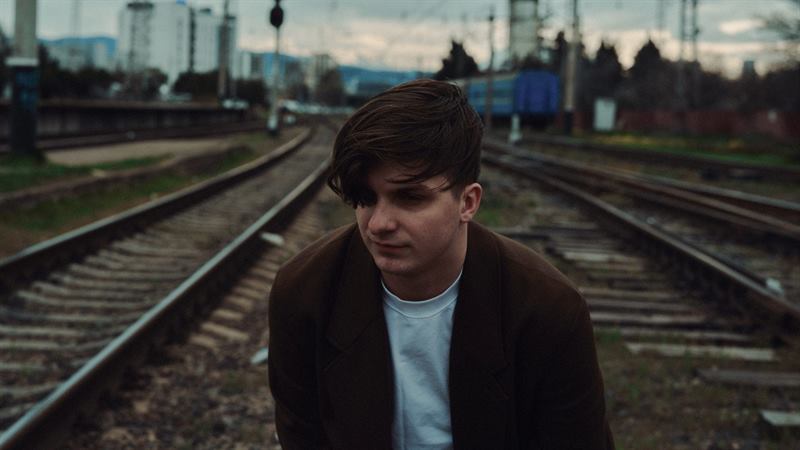 A young man standing between railway tracks