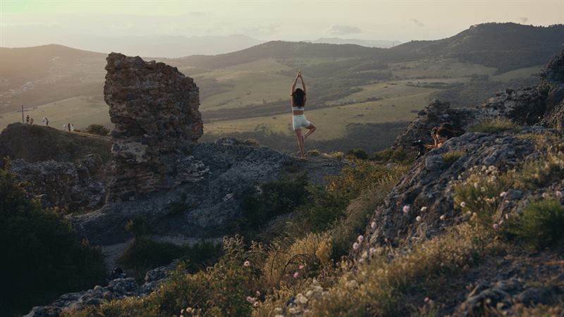 A person standing on a ruined wall above a green valley
