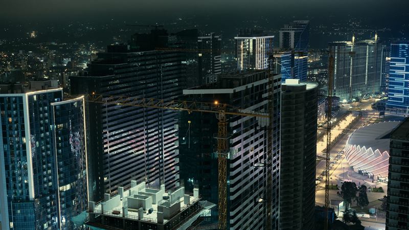 High-rise towers and cranes above a city at night