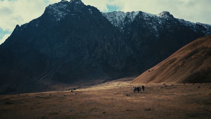 A small group walking under a dark rock face