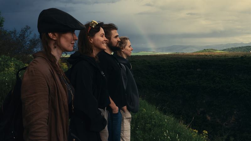 Four friends standing together on a green ridge