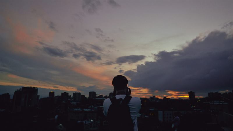 A person photographing a city skyline at sunset