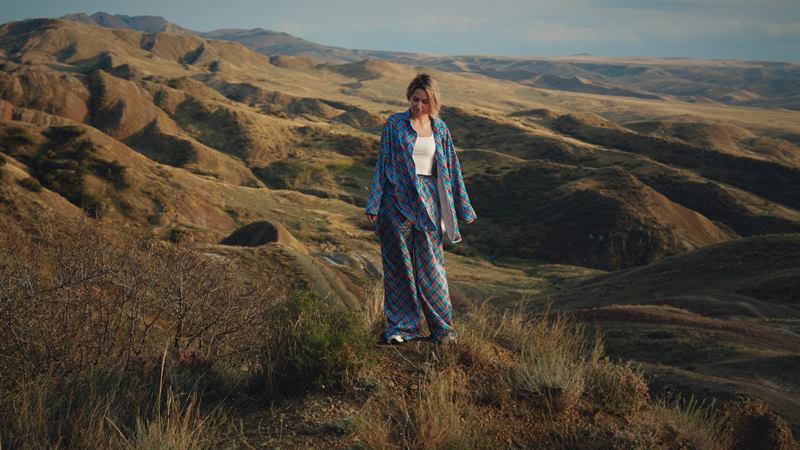 A woman in a striped robe walking a bare hillside