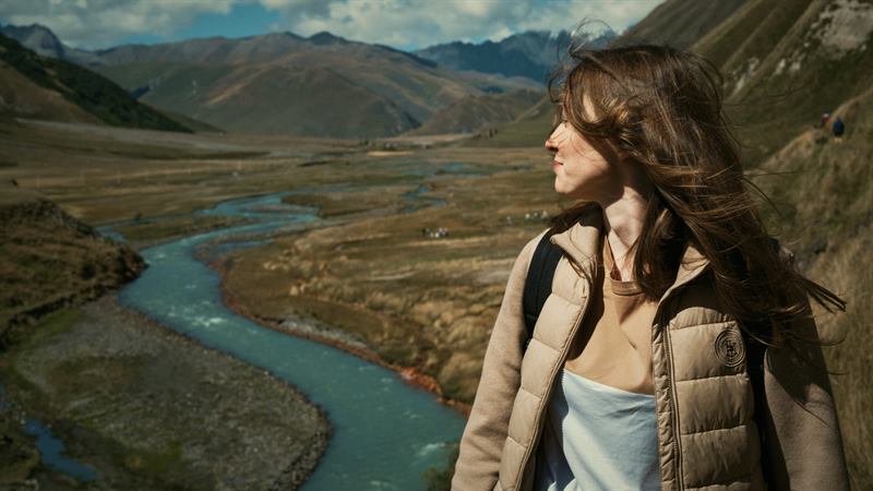 A woman looking out over a turquoise river in a wide valley