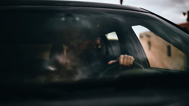 A hand on the wheel inside a dark car